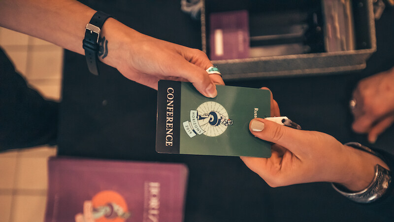 A conference badge being handed across the registration table.
